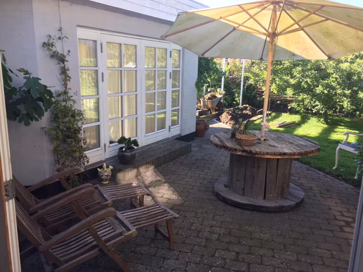 The town house's terrace with a parasol, garden table and deck chairs by French doors