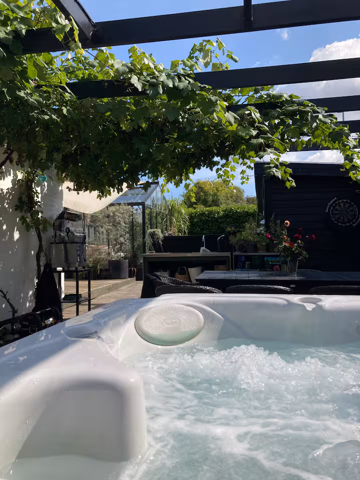 The villa's hot tub under a vine pergola with a terrace facing the garden